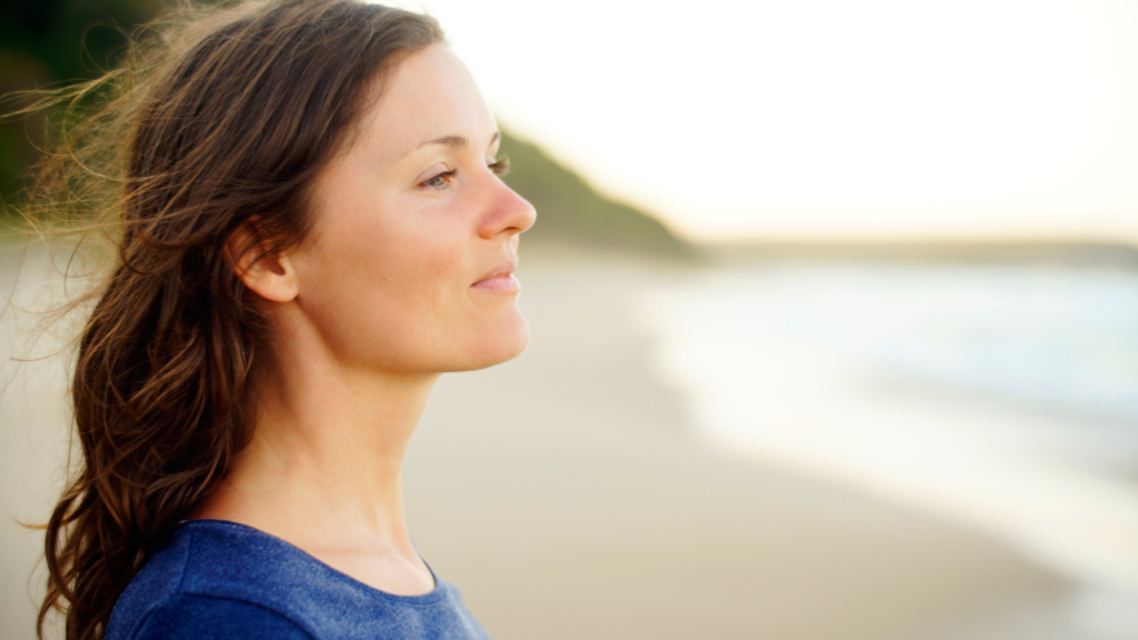 A woman stands by a lake, looking into the distance with assurance, embodying strength and hope as she copes with the challenges of divorce.