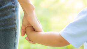 A woman holds a child's hand, symbolizing protection and safety, representing the support and security provided by an Illinois Order of Protection.