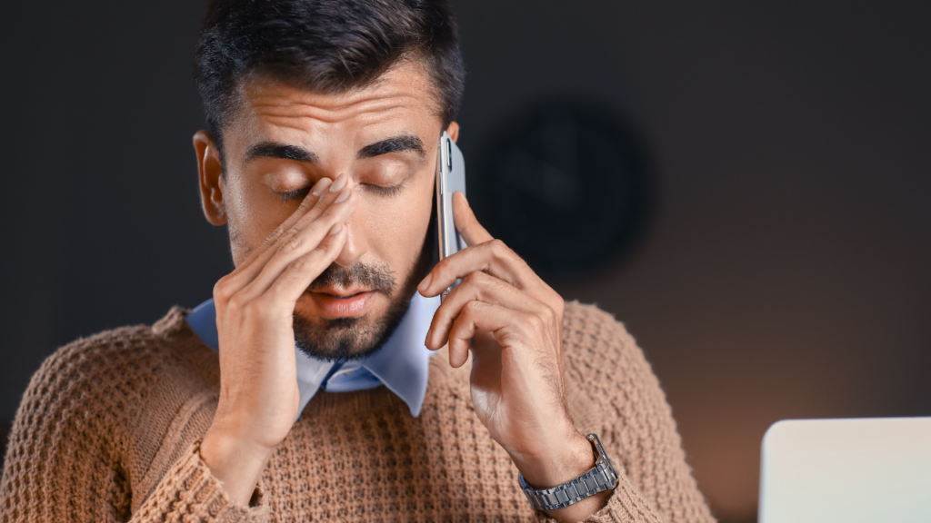 Frustrated man holding phone to ear, dealing with a co-parent who refuses to communicate.