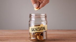 Hand placing a coin into a glass jar labeled 'Pension' filled with gold coins.