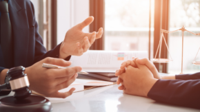 Two people discussing a parenting plan in a legal office with a gavel and justice scale on the table.